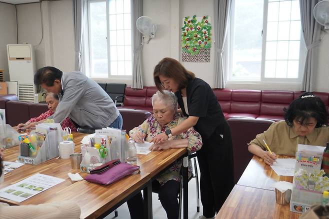 정진아 샬롬기억돌봄학교 원장(오른쪽 두번째)이 어르신들의 글쓰기 활동을 돕고 있다.
