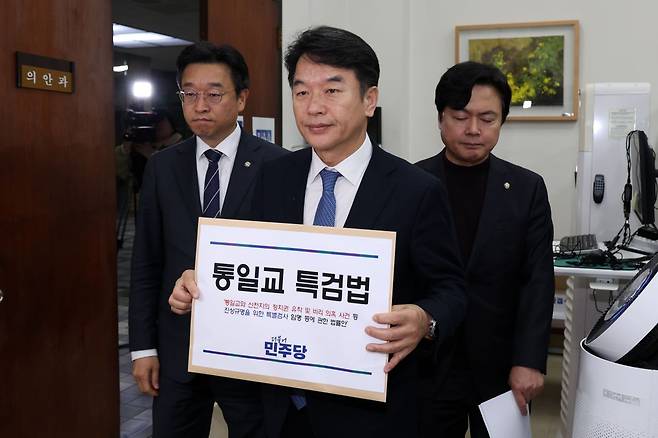 더불어민주당 관계자들이 지난해 12월 26일 서울 여의도 국회사무처 의안과에서 통일교 특검법안을 제출하기 전 서류를 들어보이는 모습. 연합뉴스
