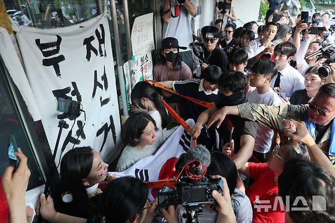 [서울=뉴시스] 이영환 기자 = 6·3지방선거 투표용지 부족 사태로 촉발된 잠실 개표소 봉쇄 시위가 12일째 이어진 지난 16일 서울 송파구 올림픽공원 핸드볼경기장 개표소 앞에서 시민들이 국민의힘과 대한체육회 관계자들의 진입을 봉쇄하고 있는 모습. 문 앞 돌아선 채 고개를 숙이고 있는 여성이 일명 '올다르크'(공동취재) 2026.06.16. photo@newsis.com
