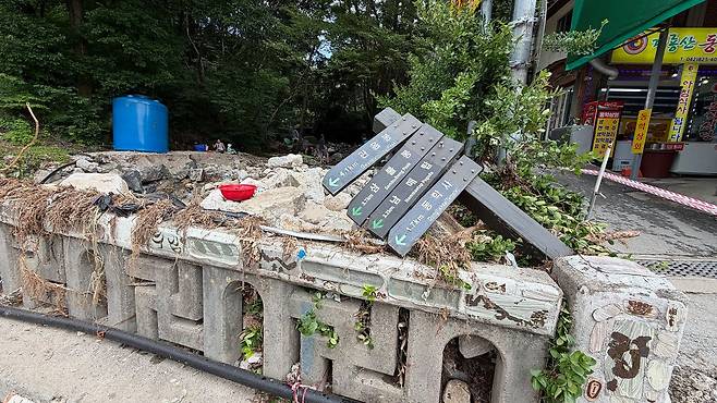 11일 오전 10시 충남 공주시 반포면 계룡산 동학사 입구에 지난 9일 내린 폭우로 안내판이 부서진 채로 방치돼 있다. 난간에는 물살에 떠내려 온 커다란 돌이 그대로 쌓여 있다. 신진호 기자