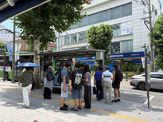 나무 그늘에 모여 버스 기다리는 시민들 [촬영 김채린]