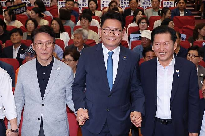 김민석(왼쪽부터)·송영길·정청래 더불어민주당 당대표 후보가 12일 서울 여의도 국회 의원회관에서 열린 전국자치분권민주지도자회의 당대표 후보 정견 발표에서 손을 잡고 기념 촬영하고 있다. 뉴스1