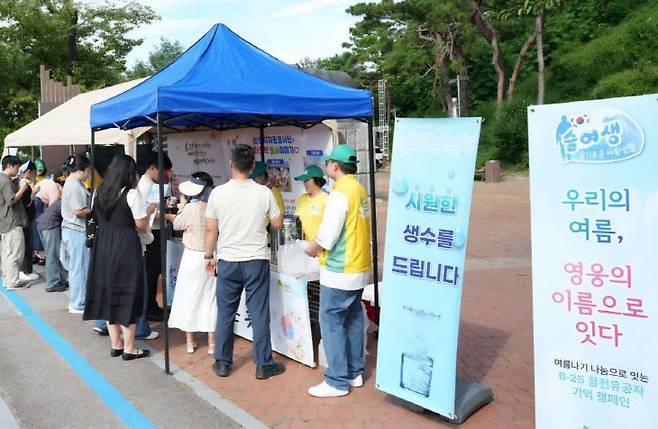 신천지자원봉사단 공주지부 봉사자들이 25일 충남 공주시 곰탑공원에서 열린 '6·25 참전유공자 기억 캠페인'에서 시민들에게 생수와 부채를 나누며 보훈문화 확산 활동을 펼치고 있다. (사진=신천지자원봉사단 공주지부 제공)