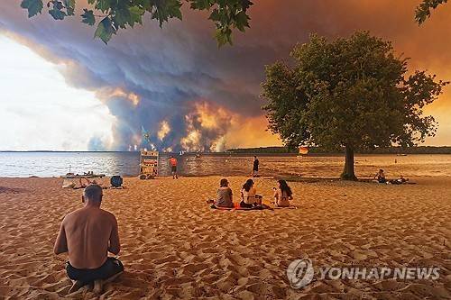24일 프랑스 남서부 해안가 피서객들 눈앞에 거대한 산불 연기가 피어오르고 있다. [AFP=연합뉴스. 재판매 및 DB 금지]