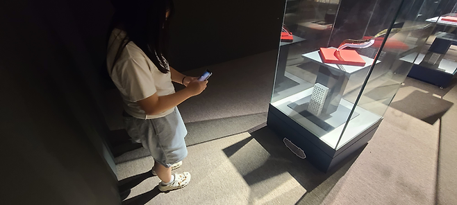 ▲ 한 어린이 관람객이 29일 의성조문국박물관 특별기획전 전시공간에서 '유물 찾기 프로젝트'에 참여해 진열대 아래 부착된 유물 모양 보드판을 스마트폰으로 촬영하고 있다. 의성군 제공