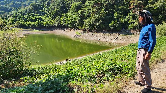 경남 밀양시 무안면 영안마을에 거주하는 이상용씨(77)가 수위가 크게 낮아져 흙이 드러난 저수지를 바라보고 있다. 예년 같으면 이 시기 나무 바로 아래까지 물이 차 있어야 한다.