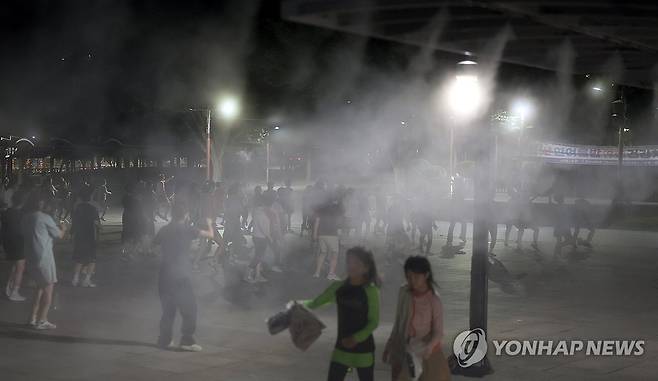 쿨링포그 작동하는 밤  29일 오후 경남 양산시 물금읍 양산워터파크에서 열린 건강 체조 교실에서 많은 시민이 안개형 냉각수(쿨링포그) 도움을 받아 체조하고 있다. 
    이날 오후 8시 40분 기준 현장 기온은 33도, 이날 양산 낮 기온은 40.3도를 기록했다. [연합뉴스 자료사진]