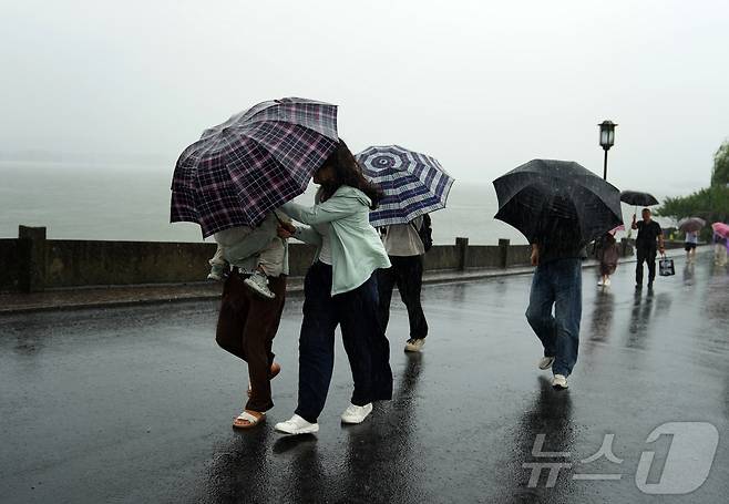 9일 중국 동부 저장성 항저우의 서호 풍경구 단교(두안차오)에서 관광객들이 빗속을 걷고 있다. 제13호 태풍 '돌핀'이 접근함에 따라 중국 중앙기상대는 일요일 태풍 경보 체계 중 가장 높은 단계인 적색경보를 발령했다. 2026.08.09. ⓒ 신화=뉴스1