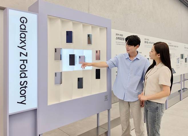 삼성전자 모델들이 서울 삼성 강남에 마련된 '폴더블 헤리티지'의 '갤럭시 폴드·플립 스토리' 섹션에서 역대 갤럭시 폴더블 라인업을 확인하고 있다. 삼성전자 제공