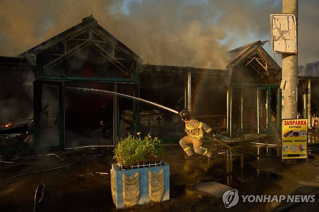 16일 우크라이나 수도 키이우에서 러시아 미사일 공격을 받은 책 시장에서 소방관이 불을 끄고 있다. [AP=연합뉴스. 재판매 및 DB 금지]