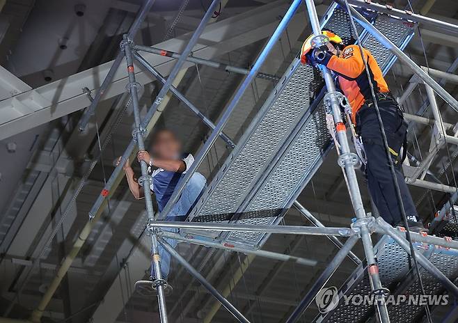 민주당 전당대회장 고공 시위 (대전=연합뉴스) 황광모 기자 = 17일 대전 컨벤션센터에서 열린 제3회 더불어민주당 정기 전국당원대회에서 한 당원이 조명탑에 올라가 시위를 벌이고 있다.
   시위자는 자진해 조명탑에서 내려왔지만 경찰에 현행범으로 체포됐다.
   이 소동으로 민주당 전당대회가 20여분간 지연됐다. 2026.8.17 [공동취재] hkmpooh@yna.co.kr