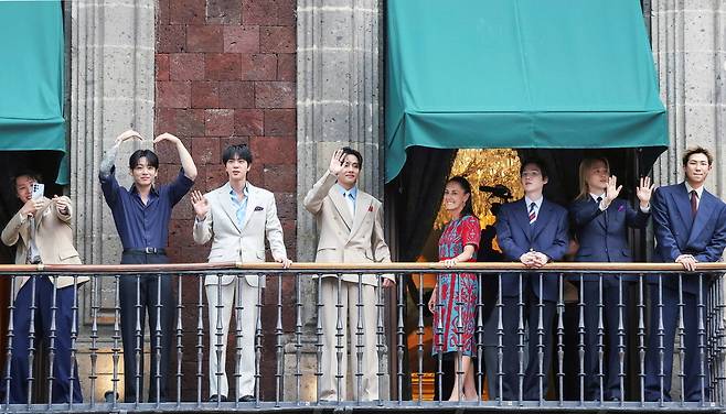 O grupo BTS cumprimenta os fãs que lotam a Praça Zócalo, na Cidade do México, ao lado da presidente mexicana Claudia Sheinbaum, da sacada do Palácio Presidencial, em 6 de maio (horário local). Reuters/Yonhap News