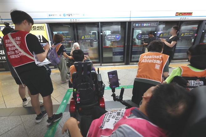 전국장애인차별철폐연대(전장연) 소속회원들이 지난 18일 서울역에서 ‘출근길 지하철 탑니다’ 시위를 하고 있는 가운데 4호선 열차가 무정차 통과하고 있다. [연합뉴스]