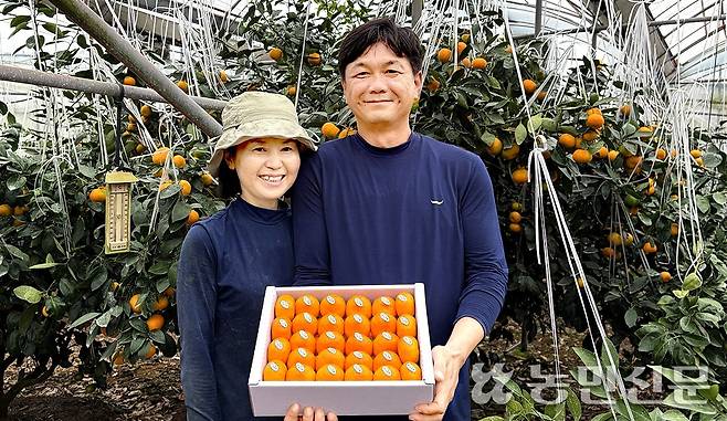 좌태산·이은영씨 부부가 수확한 하우스감귤을 들고 환하게 웃고 있다.