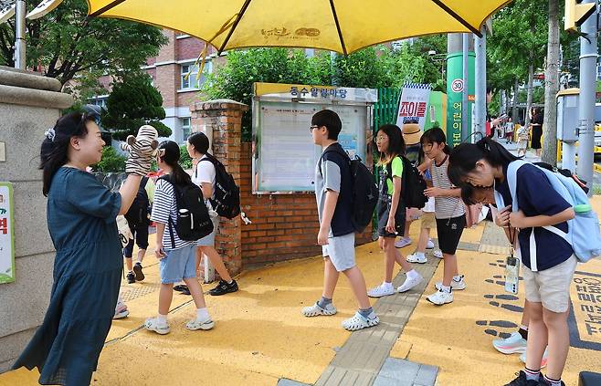 지난 11일 여름방학을 마치고 개학한 인천의 한 초등학교 앞에서 등교하는 학생들이 교장선생님과 인사하고 있다. 연합뉴스