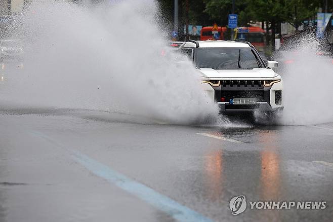 고인 빗물 가르는 승용차 [연합뉴스 자료사진]