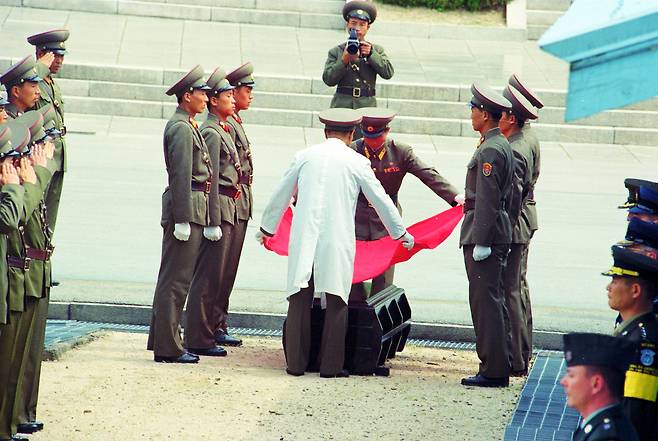 1999년 8월 25일 판문점에서 북한군이 수해 때 남측으로 떠내려온 북한군 시신 1구를 유엔군 측으로부터 인계받아 이동하며 붉은 천을 덮고 있다. 이제원 기자