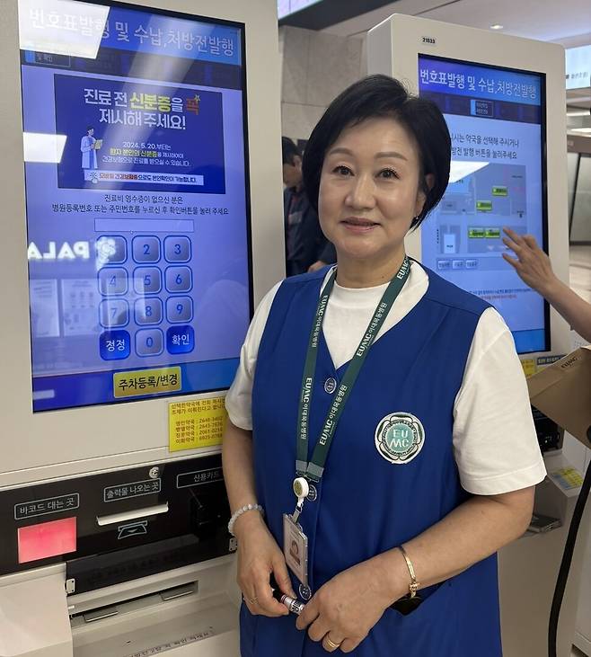 무인기계(키오스크) 옆에 서서 23년째 병원을 방문하는 사람들을 돕고 있는 신정희씨. 남궁인 작가 제공