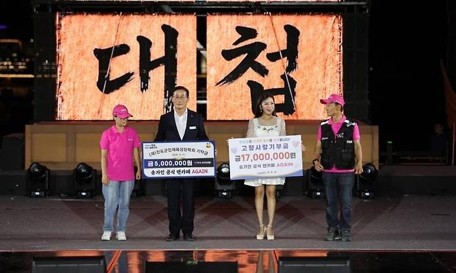 송가인의 팬클럽 ‘어게인’ 회원들이 지난 12일 열린 명량대첩축제 기간 열린 ‘명량 트로트의 밤’ 공연에서 진도군에 성금을 전달하고 있다. 진도군
