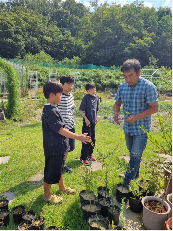 아이들이 주민과 함께 모종을 살펴보고 직접 심으며 자연과 교감하는 상주시 공성면 영오리 리빙랩 현장. 흙과 식물을 매개로 정서적 안정과 공동체 관계를 키우는 원예치유체험을 진행하고 있다.