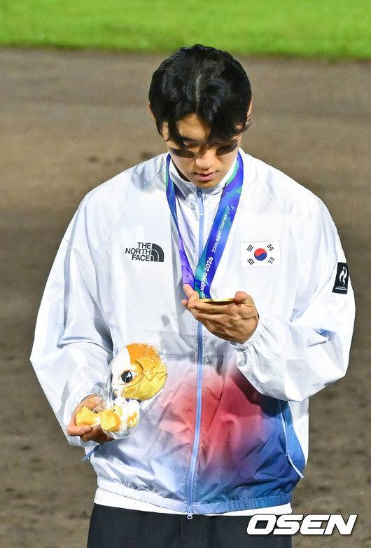 [OSEN=도요하시(일본), 박준형 기자] 한국야구가 우여곡절 끝 아시안게임 5회 연속 금메달을 해냈다.&nbsp;류지현 감독이 이끄는 한국 야구대표팀은 27일 일본 아이치현 도요하시 시민구장에서 열린 2026 아이치-나고야 아시안게임 일본과 결승전에서 3-1로 승리했다.시상식에서 김도영이 금메달을 바라보고 있다.    2026.09.27 / soul1014@osen.co.kr