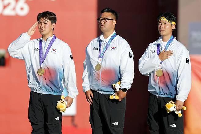 2일(현지 시간) 일본 아이치현 오카자키시 오카자키 중앙종합공원 내 다목적 광장에서 열린 2026 아이치·나고야 아시안게임 양궁 리커브 남자 단체 시상식에서 금메달을 획득한 김우진(가운데), 이우석, 김제덕(맨 왼쪽)이 국민의례를 하고 있다. [오카자키(일본)=뉴시스]