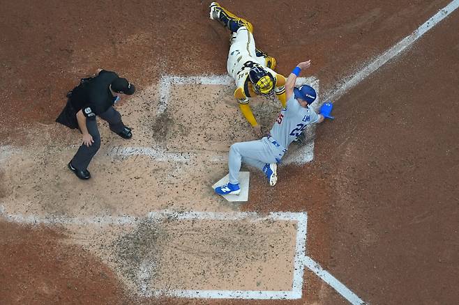 Los Angeles Dodgers second baseman Tommy Edman, left, scores on an RBI sacrifice fly hit by Freddie Freeman as Milwaukee Brewers catcher William Contreras reaches for the tag during the fifth inning of Game 2 of baseball's National League Championship Series between the Milwaukee Brewers and the Los Angeles Dodgers, Monday, Oct. 12, 2026, in Milwaukee. (AP Photo/Abbie Parr)        <저작권자(c) 연합뉴스, 무단 전재-재배포, AI 학습 및 활용 금지>