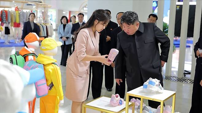 김정은 북한 국무위원장이 지난 19일 '전국피복, 신발전시회-2026'을 찾아 딸 주애가 들어 보이는 분홍색 아동용 운동화를 살펴보고 있다. 조선중앙TV 화면=연합뉴스