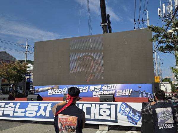 21일 오후 한화오션 거제조선소 서문 앞에서 열린 '한화오션 원청교섭 투쟁 승리! 현장탄압 분쇄! 금속노동자 결의대회'에서 강인석 거제통영고성하청지회장이 영상으로 연결해 발언하고 있다. /표세호 기자