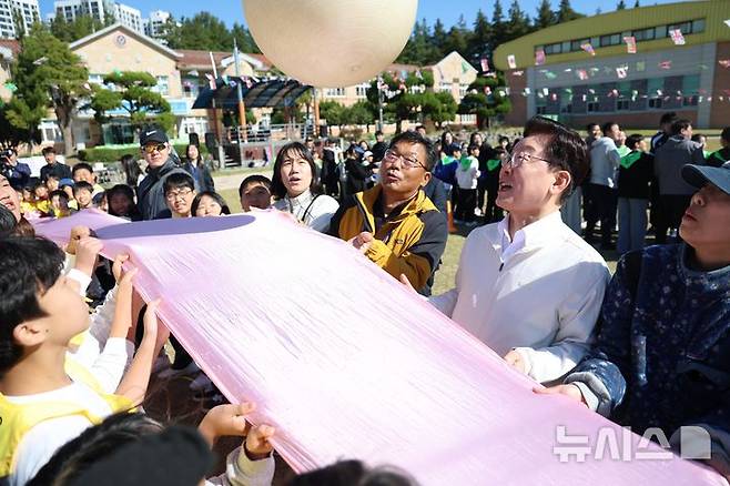 [익산=뉴시스] 김진아 기자 = 이재명 대통령이 22일 전북 익산 왕궁초등학교에서 열린 가을 행복학교 체육한마당에서 학생들과 '짐볼 이동하기'를 하고 있다. 2026.10.22. bluesoda@newsis.com