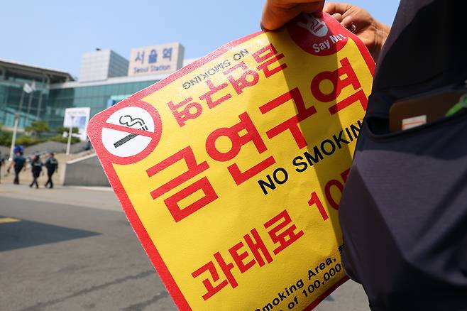 서울역광장에서 구청 관계자가 '금연구역' 안내 스티커를 들고 있다. 뉴스1