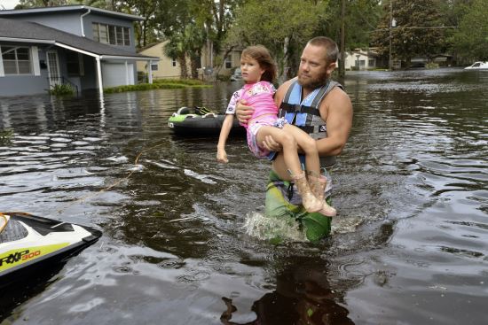 (플로리다 타임즈-유니온/AP뉴시스) 토미 네비트가 홍수로 불어난 플로리다주 잭슨빌에서 6살 어린이 미란다 에봇을 구하고 있다.