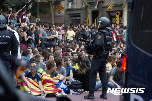 【바르셀로나=AP/뉴시스】스페인 경찰관이 20일(현지시간) 카탈루냐에 있는 극좌 정당 민중연합후보당(CUP)의 당사 앞에 서 있고 시위대가 경찰 단속에 항의하고 있다. 2017.09.21