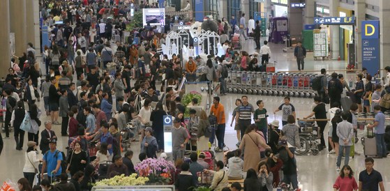 추석연휴 8일 오후 입국한 여행객들이 공항 청사를 가득 메웠다. 한 조사에 따르면 10일 이상 쉬는 기업은 300인 이상의 경우 88.6%인 반면, 300인 미만의 경우엔 56.2%에 그쳤다. [중앙포토]