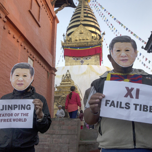 망명한 티베트 활동가들이 18일 네팔 수도 카트만두에서 시진핑 가면을 쓴 채로 시진핑을 비판하는 손팻말을 들어보이고 있다. 카트만두 | EPA연합뉴스