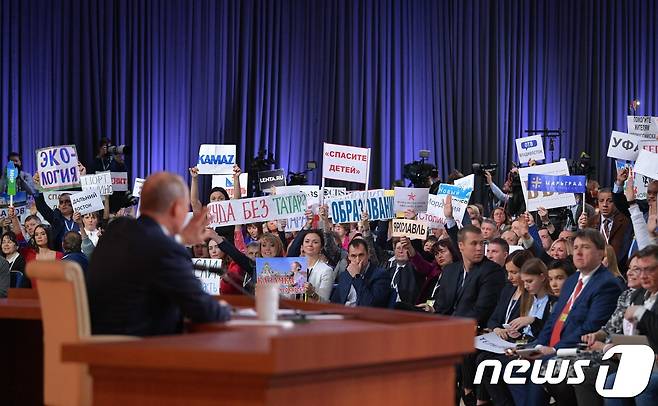 14일(현지시간) 블라디미르 푸틴 러시아 대통령의 연례 기자회견에 참석한 내외신 기자들이 피켓을 들고 질문자 선정을 기다리고 있다.© AFP=뉴스1