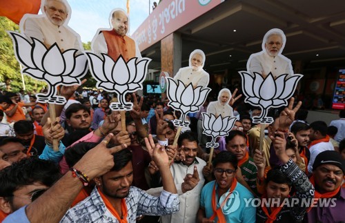 18일 인도 서부 구자라트 주 간디나가르에서 여당 인도 국민당 지지자들이 나렌드라 모디 인도 총리와 아미트 샤 BJP 총재 사진을 들고 선거승리를 축하하고 있다.[EPA=연합뉴스]