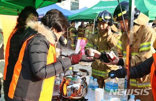 【제천=뉴시스】강신욱 기자 = 22일 충북 제천시 하소동 한 복합건축물 화재 현장 앞에서 제천시여성의용소방대원들이 소방관들에게 따끈한 차 등을 대접하고 있다. 2017.12.22. ksw64@newsis.com