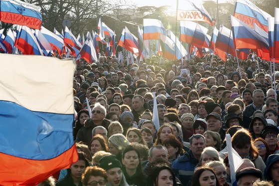 14일(현지시간) 세바스토폴의 나히모프 광장에서 열린 크림반도 합병 4주년 기념 행사에서 시민들이 러시아 국기를 펄럭이며 블라디미르 푸틴 러시아 대통령의 연설에 환호하고 있다. [EPA=연합뉴스]