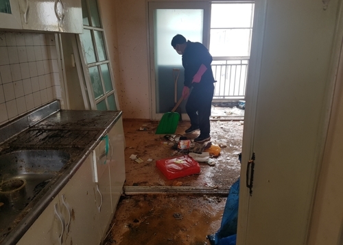 쓰레기·오물로 뒤덮인 아파트를 청소하는 경찰관 [광주 서부경찰서 제공=연합뉴스]