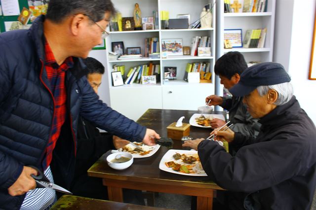 서영남(왼쪽 첫번째) 민들레국수집 대표가 지난 26일 식사 중인 한 노숙자에게 직접 김을 얹어 주고 있다.