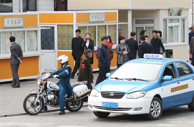 평양 창전거리에서 교통경찰 오토바이와 택시가 신호 대기를 하고 있다.