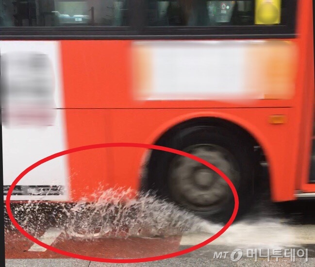 14일 오전 8시50분쯤 서울 광화문역 인근 횡단보도에서 한 대형버스가 물웅덩이를 지나며 빗물을 튀기고 있다./사진=남형도 기자