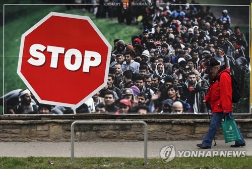 헝가리 정부의 반이민 입간판 앞을 지나는 헝가리 부다페스트 시민[AP=연합뉴스]