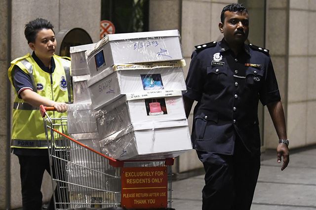 말레이시아 경찰이 18일 나집 라작 전 총리 소유의 주택에서 압수한 물품들을 쇼핑카트로 실어나르고 있다. 쿠알라룸푸르=EPA연합뉴스