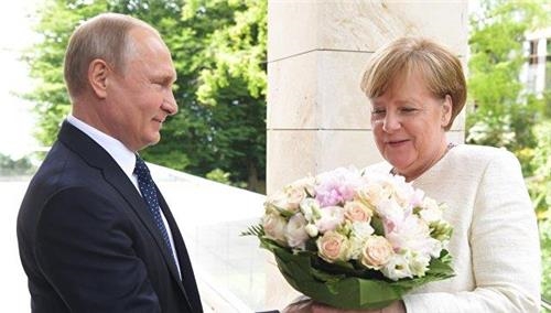 지난 18일 소치를 방문한 메르켈 총리(오른쪽)에게 꽃다발을 선물하는 푸틴 대통령 [리아노보스티=연합뉴스]