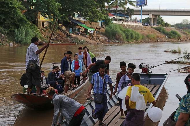배를 타고 모에이강을 건너 매솟으로 넘어오는 버마 노동자들. 타이-버마를 잇는 우정의 다리(사진 오른쪽 위)는 여권과 노동허가증 없는 버마 노동자들에게는 비정한 다리일 뿐이다. 정문태 제공