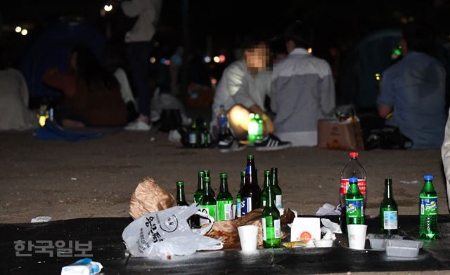 지난 21일 오후 서울 영등포구 여의도한강공원에서 시민들이 술을 즐기고 있는 가운데, 누군가 치우지 않고 떠난 자리에 술병과 음식 쓰레기 등이 뒹굴고 있다. 배우한 기자