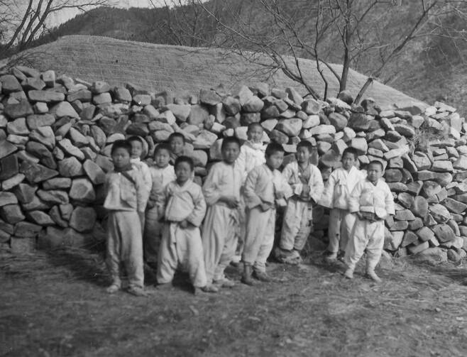 1951. 2. 6. 한국 산골마을 아이들이 돌담 앞에서 지나가는 유엔군들을 물끄러미 바라보고 있다. ⓒNARA