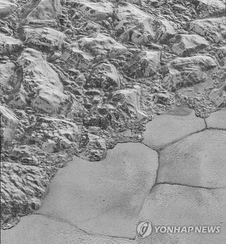 명왕성 산맥과 평원 사이에 주름(사진 하단)처럼 형성된 얼음 알갱이 언덕. [로이터=연합뉴스]